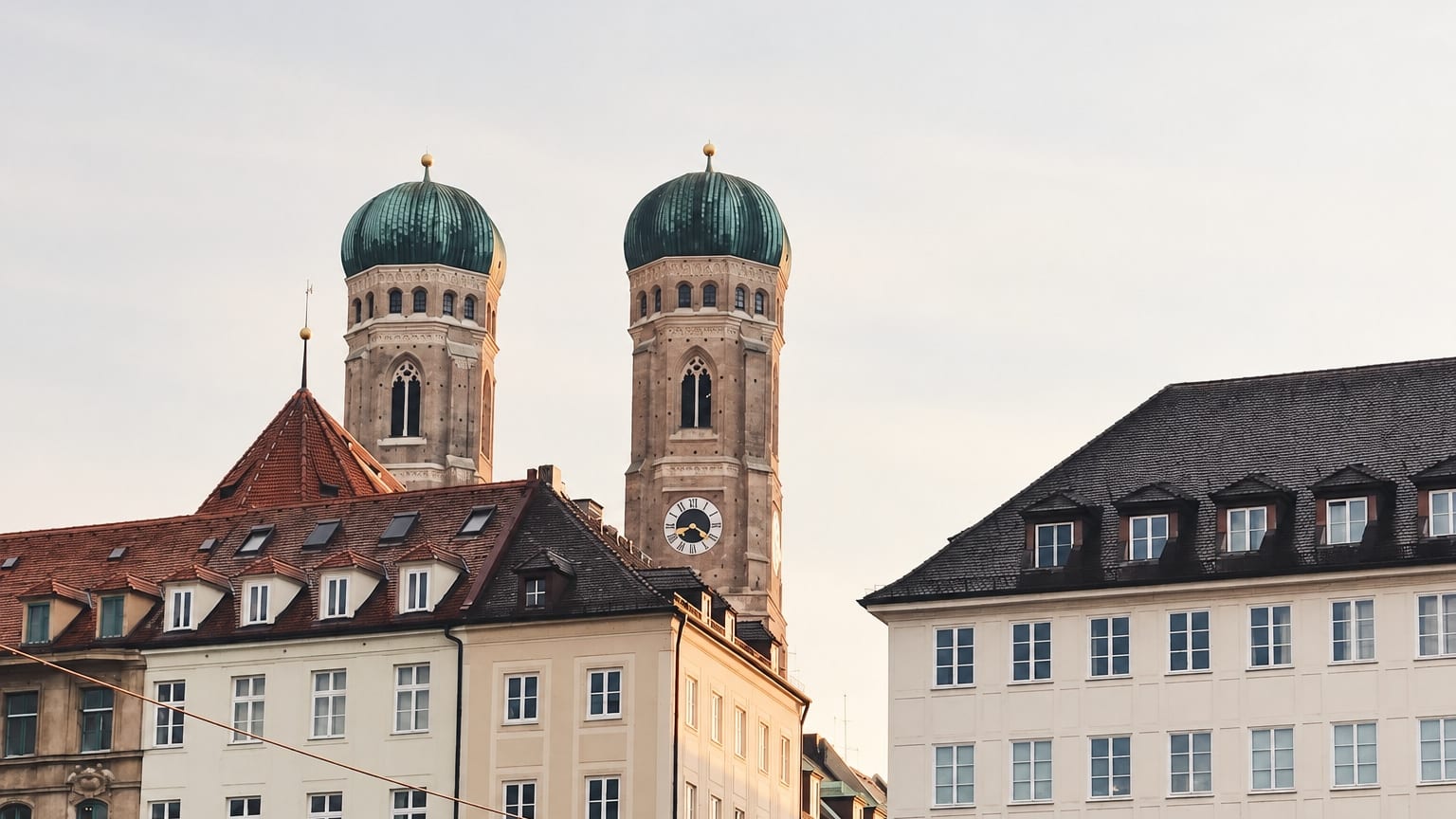 The towers of the Frauenkirche with their green domes above the rooftops of Munich's old town. Image created with AI.